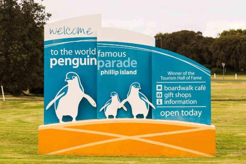 a sign for penguin paradise with three penguins on it at Tropicana Motor Inn in Cowes