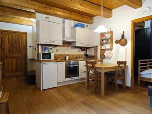 a kitchen with white cabinets and a table with chairs at Hostdomus - Via Roma Suite in Cesana Torinese
