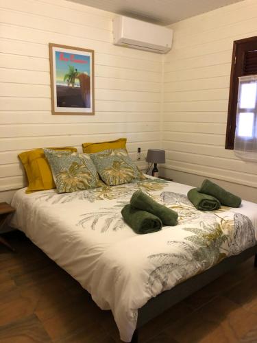 łóżko z zielonymi poduszkami w pokoju w obiekcie Les Frangipaniers de la Pelée w mieście Saint-Pierre