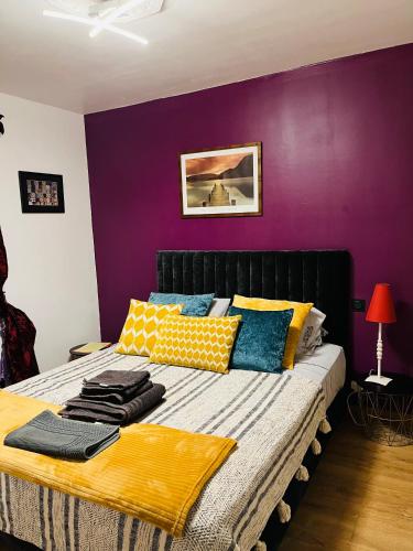 une chambre avec un lit avec un mur violet dans l'établissement Maison de Celya, à Saint-Georges-dʼOrques