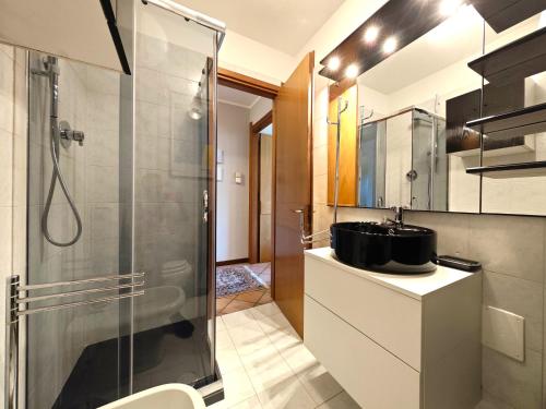 La salle de bains est pourvue d'une douche et d'un lavabo. dans l'établissement Hostdomus -Pastore Apartment, à Sestrières