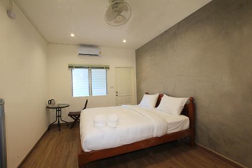 a bedroom with a bed with white sheets and a table at ZAYN Samui Hotel in Bophut