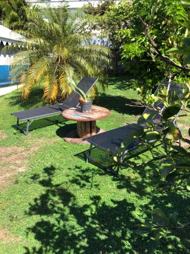a picnic table and two chairs in a yard at Les Frangipaniers de la Pelée in Saint-Pierre