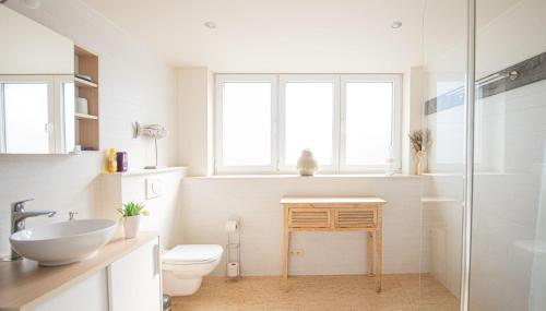 uma casa de banho branca com um lavatório e um WC em B&B De Kleine Prins em Middelkerke