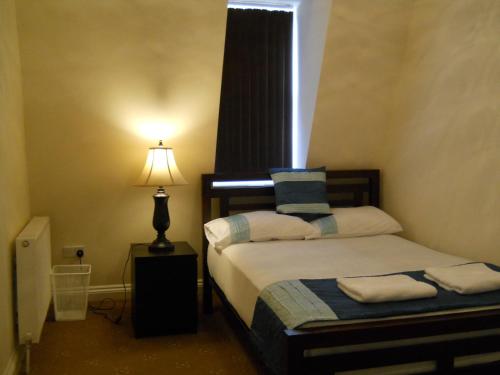 a bedroom with two beds with a lamp and a window at Citystay Guest House in London