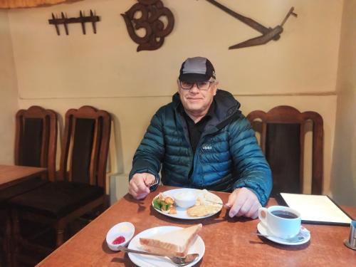 a man sitting at a table with a plate of food at HOTEL RUPAKOT AND ROOFTOP RESTAURANT in Bhaktapur