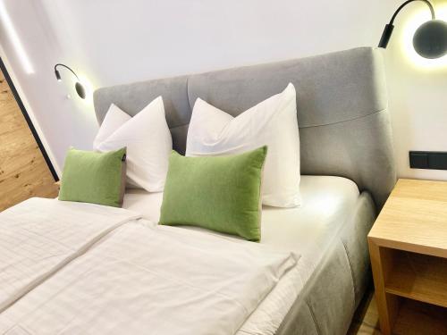 a bed with green and white pillows on it at Alpen Luxury Lodge, MARIAZELL - Adults only in Mariazell