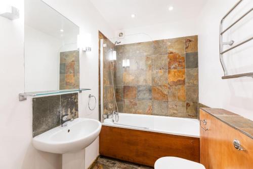 a bathroom with a sink and a tub and a toilet at Elegant 2 Bed Flat in Knightsbridge in London