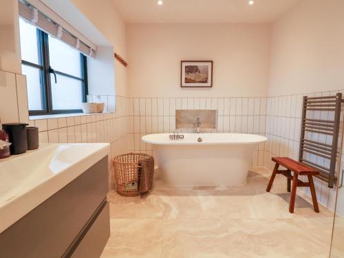 a bathroom with a tub and a sink and a chair at Grange Barn in Shrewsbury
