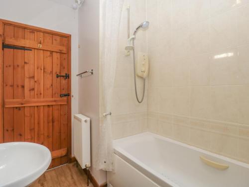 a bathroom with a shower and a tub and a sink at Anvil Cottage in Blakeney