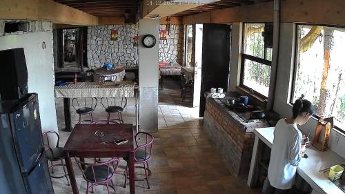Eine Frau steht in einer Küche mit einem Tisch und Stühlen in der Unterkunft Reserva y Estancia Robles Mimosos Lodge in Cartago