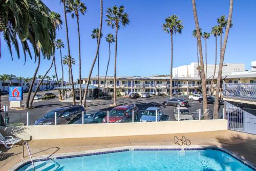 une piscine en face d'un parking avec des palmiers dans l'établissement Motel 6 San Diego, CA Airport Harbor, à San Diego