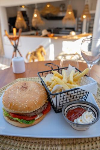 a plate with a hamburger and french fries on a table at La Maison des Vagues in Sidi Kaouki