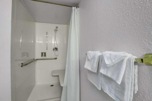 Motel 6-Napa, CA في نابا: حمام أبيض مع مناشف بيضاء على ستارة الحمام