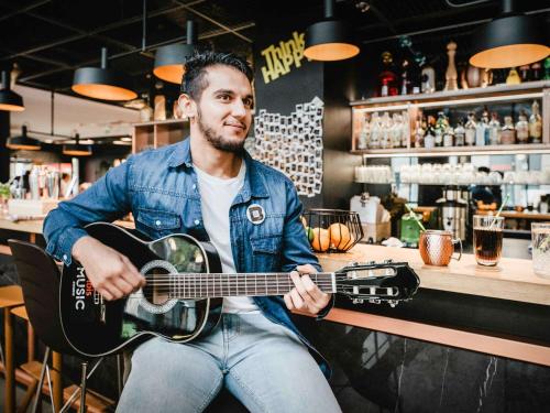 a man sitting at a bar playing a guitar at ibis Paris Bercy Village in Paris