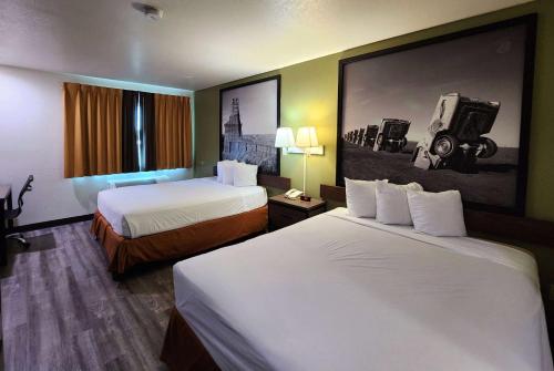 una camera d'albergo con due letti e un dipinto sul muro di Super 8 by Wyndham Austin North/University Area ad Austin