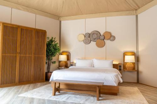 a bedroom with a white bed and two lamps at Pura Eco Retreat, Jebel Hafit Desert Park in Al Ain