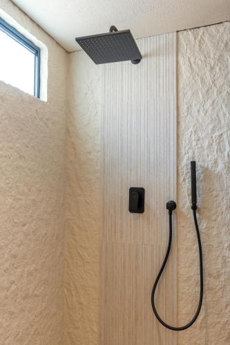 a shower in a bathroom with a shower head at Pura Eco Retreat, Jebel Hafit Desert Park in Al Ain