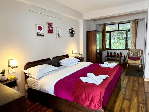 a bedroom with a large bed with two white towels on it at Darjeeling Heights - A Boutique Mountain View Homestay in Darjeeling