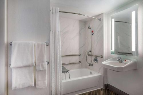 a white bathroom with a sink and a bath tub at La Quinta Inn by Wyndham Sacramento North in Sacramento