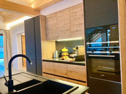 a kitchen with wooden cabinets and a sink and a stove at Alpen Luxury Lodge, MARIAZELL - Adults only in Mariazell
