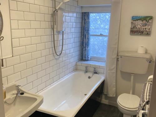 a bathroom with a tub and a toilet and a sink at Kelsey in Truro