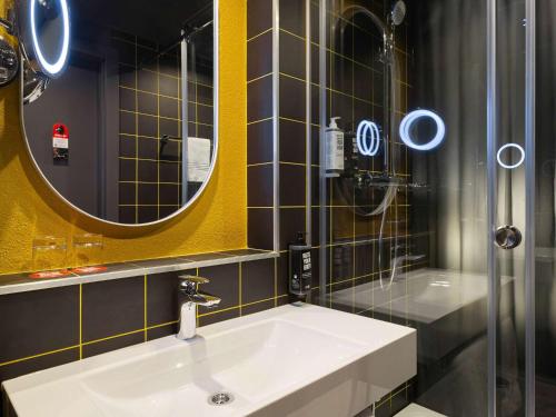 uma casa de banho com um lavatório, um espelho e um chuveiro em ibis Kyiv Beresteiska em Kiev