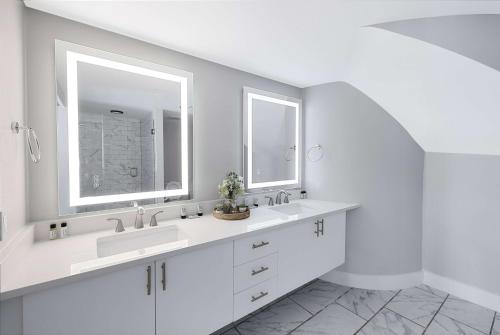 a white bathroom with two sinks and two mirrors at Georgetown Residences by LuxUrban in Washington, D.C.