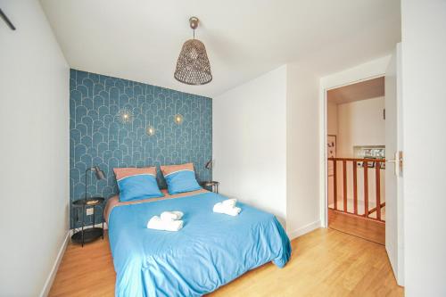 une chambre avec un lit bleu avec deux serviettes dessus dans l'établissement Le 2en1 Roissy CDG, à Longperrier