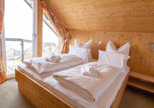 two beds in a wooden room with a window at 1A Chalet '4 Jahreszeiten' Wandern, Grillen und Jacuzzi mit Aussicht! in Bad Sankt Leonhard im Lavanttal