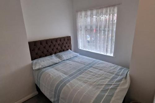 Bett in einem weißen Zimmer mit Fenster in der Unterkunft 3 Bedrooms semi-detached house,near airport,NEC in Birmingham