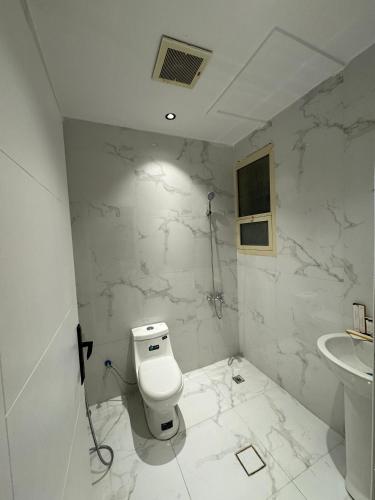 een witte badkamer met een toilet en een wastafel bij Family Modern 2BDR Apartment in Riyad