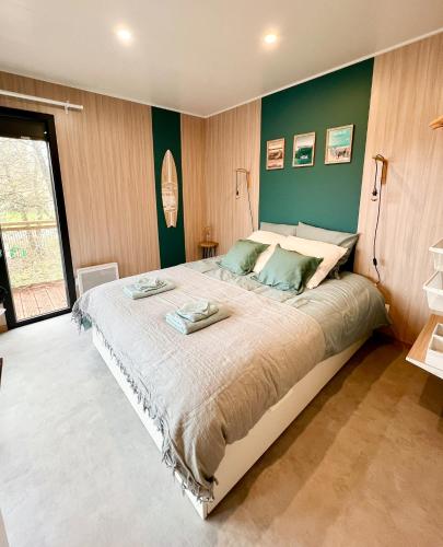 une chambre avec un grand lit aux murs verts dans l'établissement Domaine construction bois sur pilotis dans une chênaie proche océan, à Talais