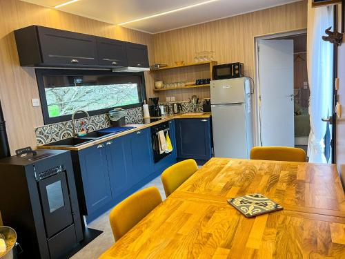 une cuisine avec une table en bois et des armoires bleues dans l'établissement Domaine construction bois sur pilotis dans une chênaie proche océan, à Talais