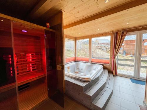 a large bathroom with a tub in a room with windows at 1A Chalet '4 Jahreszeiten' Wandern, Grillen und Jacuzzi mit Aussicht! in Bad Sankt Leonhard im Lavanttal