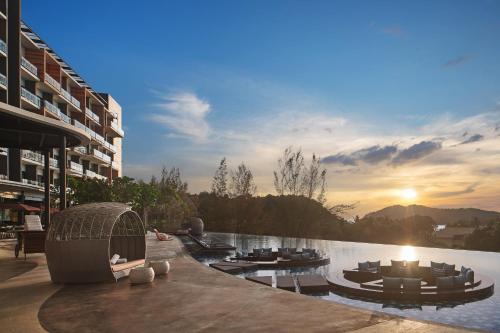 a hotel swimming pool with a sunset in the background at Aloft Langkawi Pantai Tengah in Pantai Cenang