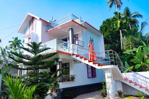 Marari Anns Casa Beach Homestay في ماراريكولام: امرأة تقف على شرفة منزل