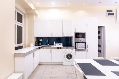 a kitchen with white cabinets and a washer and dryer at Erzsebet19 Apartment in Budapest