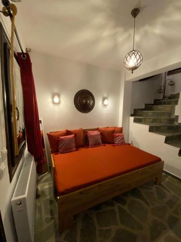 Cama naranja en habitación con escalera en La casa Varsani, en Anilio - Metsovo