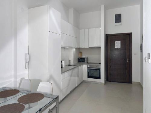 a white kitchen with white cabinets and a wooden door at Lavander Bay B01 in Donji Morinj