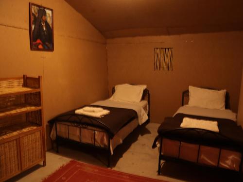 ein Zimmer mit 2 Betten und einem Regal darin in der Unterkunft Tamaris Camp in Adrouine