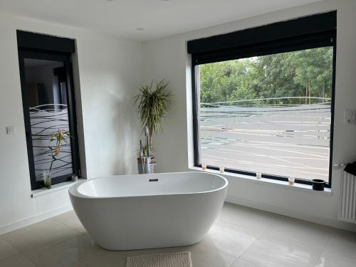 a white bath tub in a bathroom with a window at Villa piscine chauffée, jacuzzi et sauna in Mouscron