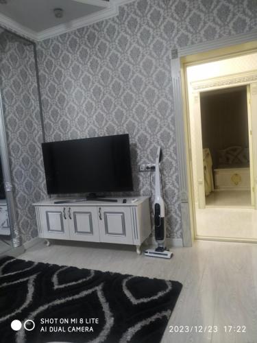 ein Wohnzimmer mit einem Flachbild-TV auf einem weißen Schrank in der Unterkunft Апартамент в центре города in Andizhan
