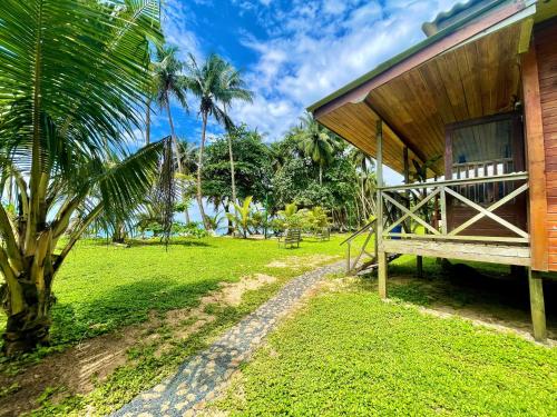 a house with a porch next to a lush green field at Domus Praia Jalé in Água-Côco