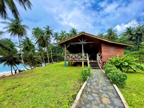 eine kleine Hütte auf einem grasbewachsenen Hügel mit Palmen in der Unterkunft Domus Praia Jalé in Água-Côco