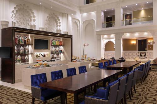 a dining room with tables and blue chairs at Sheraton Grand Pune Bund Garden Hotel in Pune