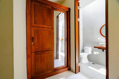 a bathroom with a wooden door and a toilet at sayana bali in Gianyar
