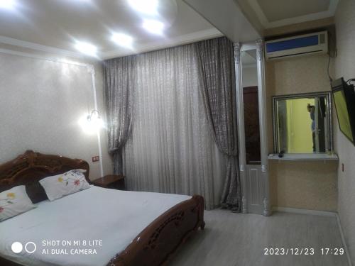 1 dormitorio con 1 cama y ventana con TV en Апартамент в центре города, en Andizhan