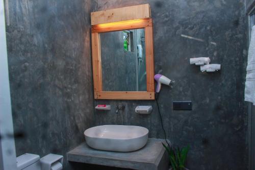 a bathroom with a sink and a mirror at Charming dark lodge in river in Weligama