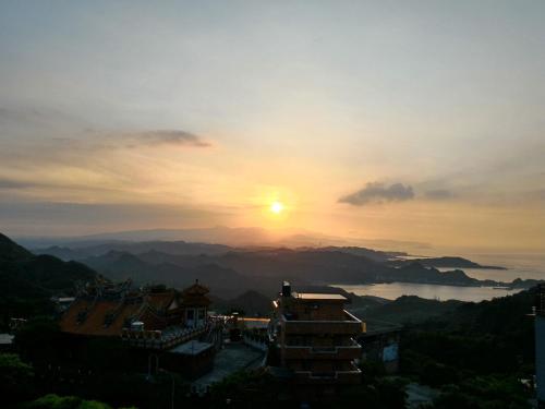a sunset with the sun setting over the mountains at Sunshine B&B in Jiufen